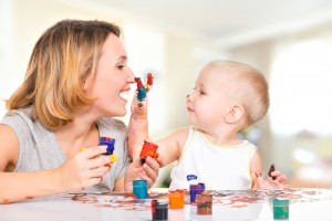 Happy child draws on the face of his mother - at home.